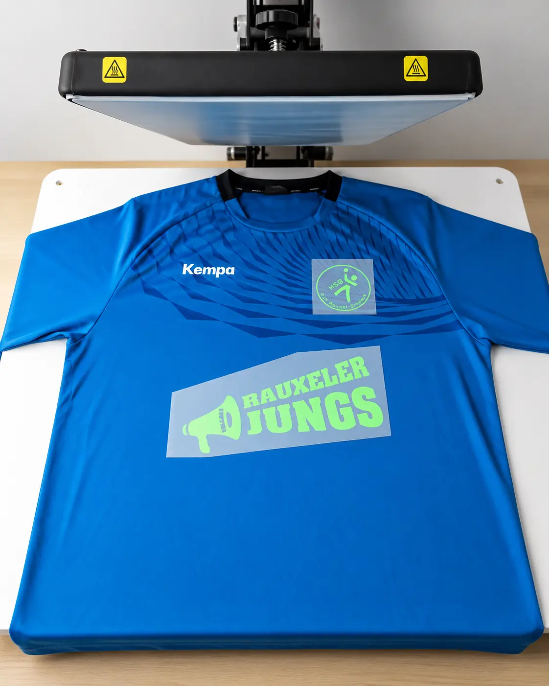 Kempa-Teamshirt mit positionierten Druckmotiven unter der Transferpresse