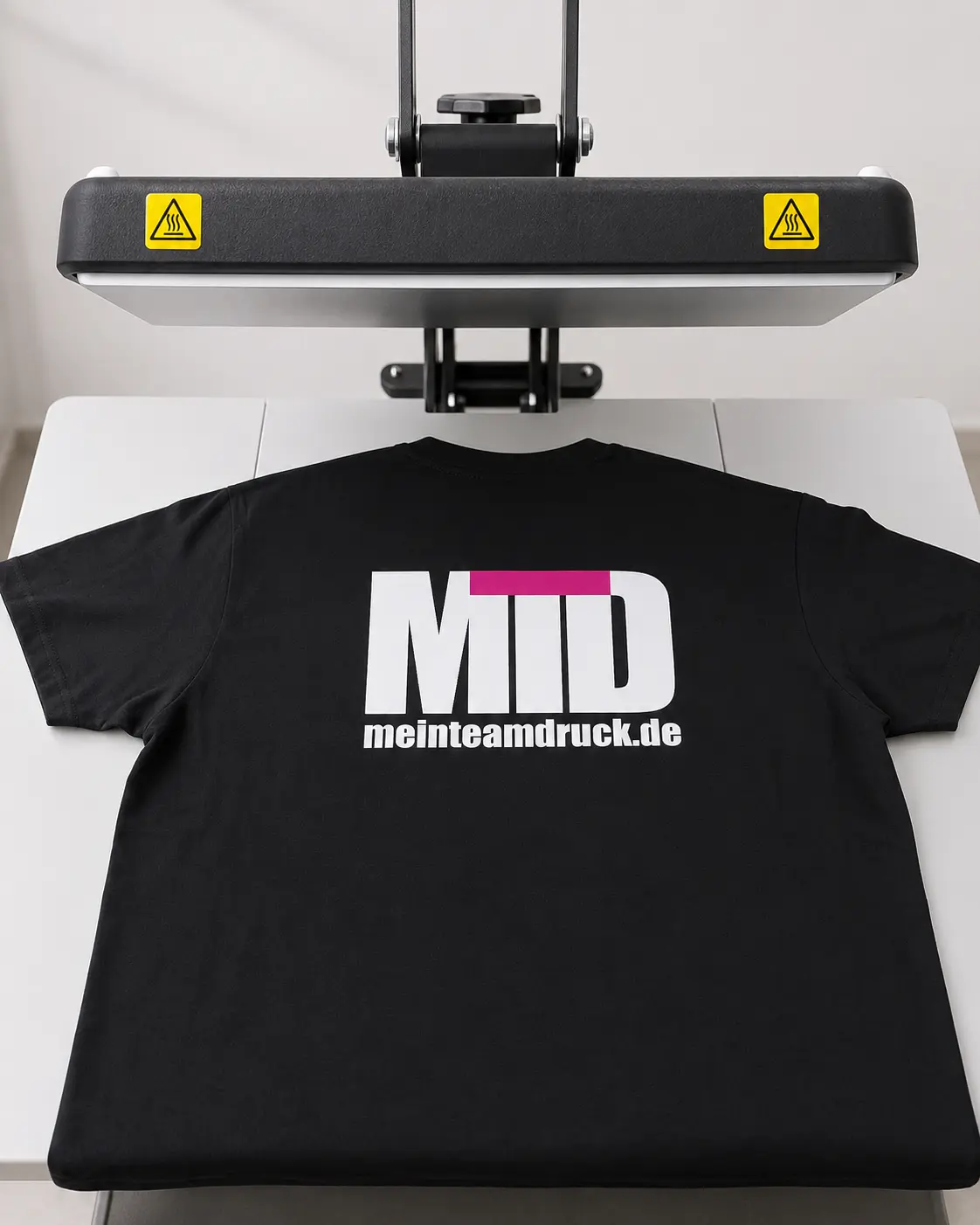 Schwarzes Shirt mit MeinTeamDruck-Aufdruck an einer Transferpresse